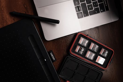 Close-up view of a workspace featuring a laptop, drawing tablet, and memory cards.